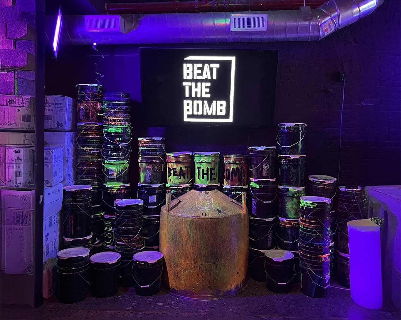 חדר עם תאורה ניאונית, פחי צבע ומיכל גדול באמצע